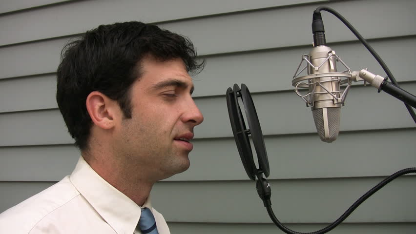 Man sings into professional condenser microphone.