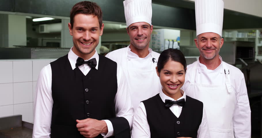 Restaurant Kitchen Staff happy restaurant staff smiling at camera in a commercial kitchen Restaurant Kitchen Staff happy restaurant staff smiling at camera in a commercial kitchen