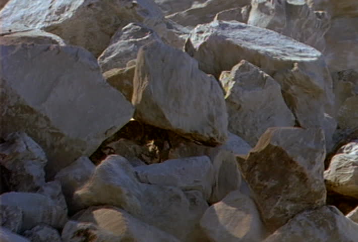 Boulders and smaller rocks roll and slide down a hill during a landslide.