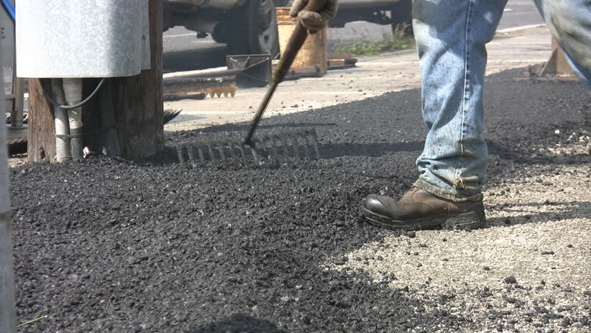 Raking hot asphalt. Man rakes and spreads hot asphalt. 