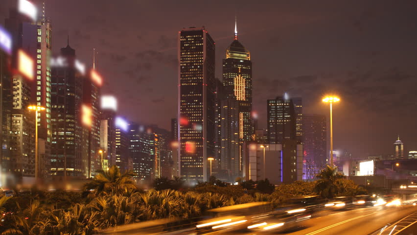 Hong Kong Sunset Cityscape Timelapse. Corporate building at the back and busy traffic across the main road at rush hour.