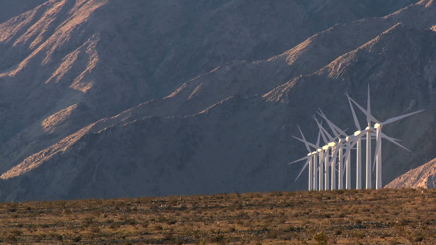 Rows of wind turbines producing clean alternative energy in barren landscape