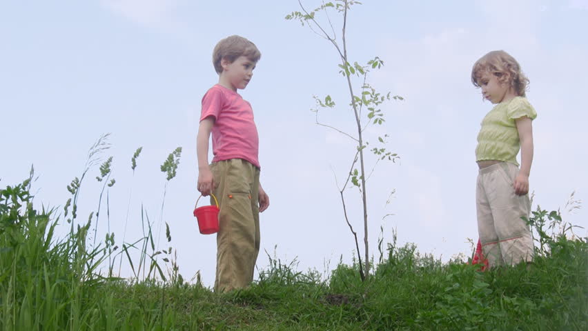 boy with bucket and girl with shovel talks about young plant 