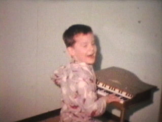 A cute brother and sister play on a cool toy piano while wearing their pajamas.