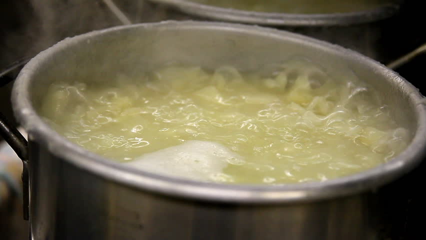 Pots cook on a stove in an industrial kitchen.