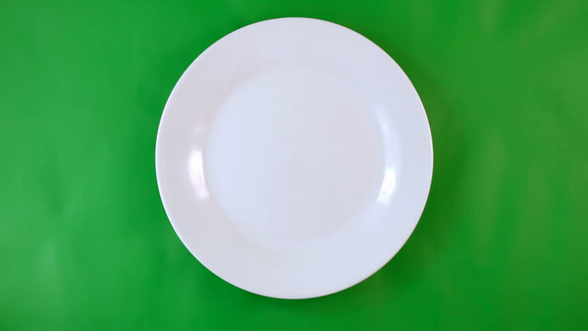 Table appointments- plate, fork, knife serving by human hands on green  background.