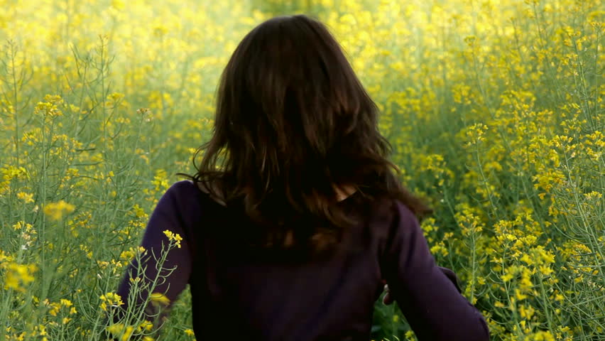 woman running away in yellow rape field