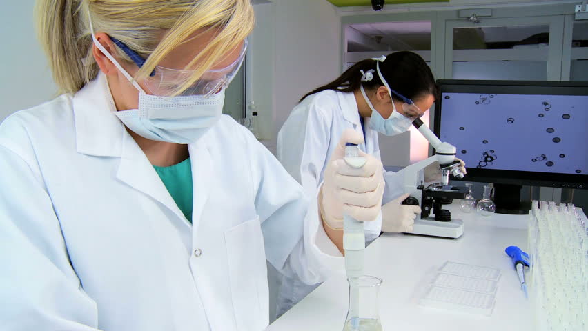 Medical researchers working with a microscope & test tubes in laboratory conditions