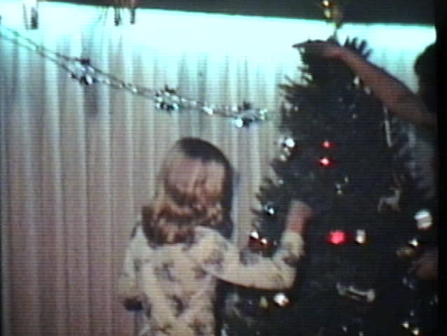 A young family has fun putting Christmas presents under the tree and spending time together during the holidays.