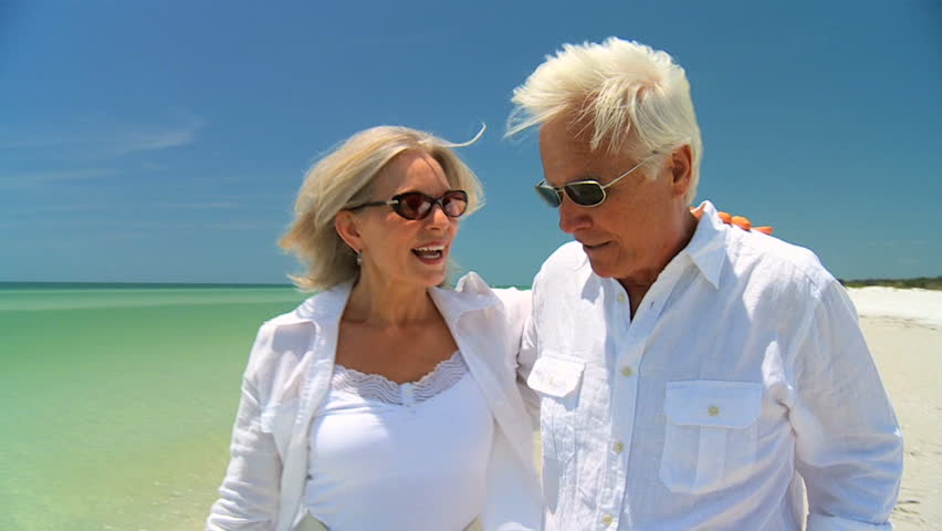 Attractive senior couple enjoying each others company walking on the beach 60FPS