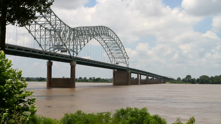 Speedboat cruises the muddy Mississippi River and goes under the Interstate 40 bridge. The bridge connects Memphis, Tennessee  with West Memphis, Arkansas across the bridge in background.