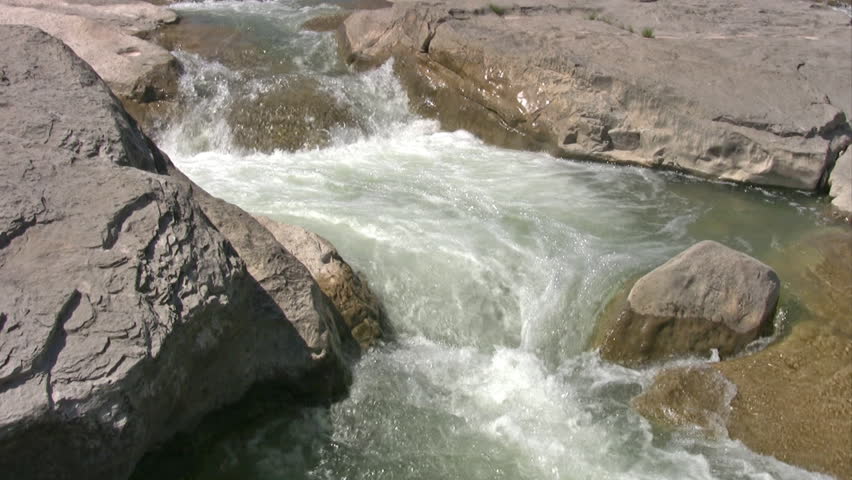 Video closeup of waterfall through smooth rock channel formation. Smooth stone river with rapids and flowing water. Cool and refreshing. 