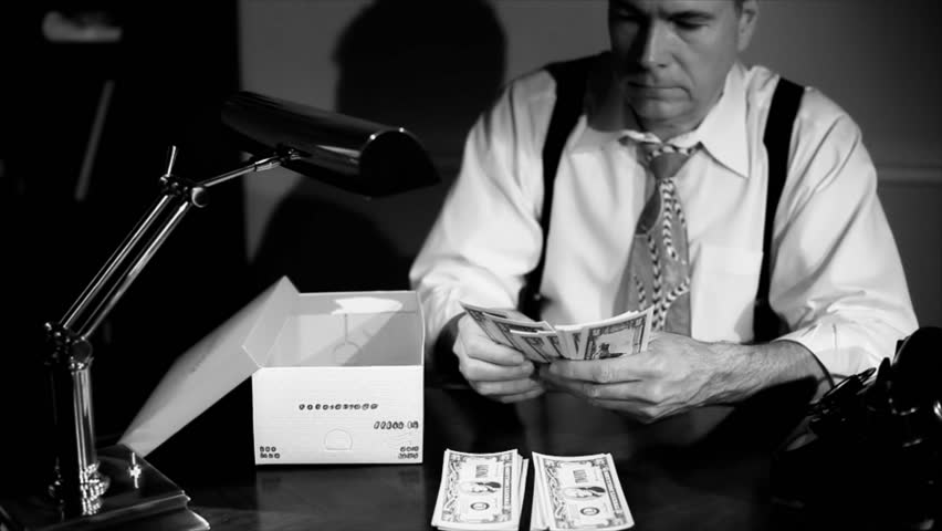 A man sitting counting money and putting it into a shoe box for safe keeping. Film Noir, Vintage look