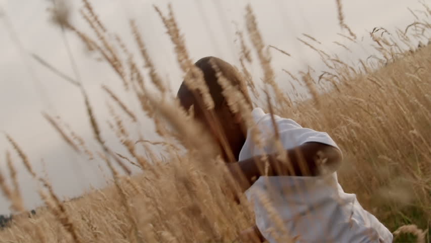 A father and son play in a wheat field on a sunny day.
