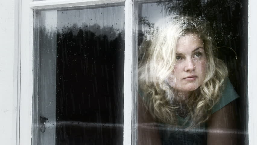 Girl looking out of a window a rainy day.