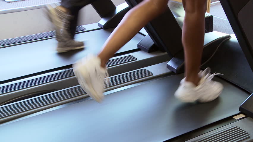 Two young women friends running on treadmill at gym