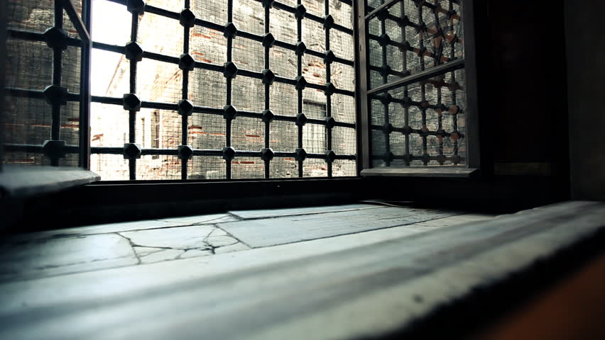 Light object passing open ancient window with iron grid and leaving trail of rose leafs / HD1080 / 30fps