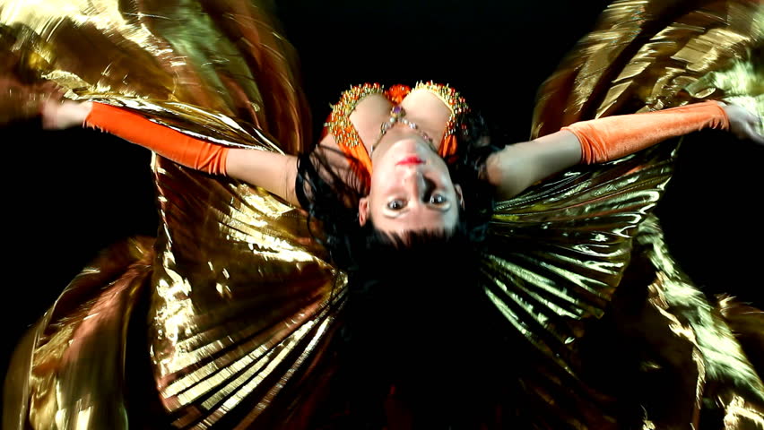 Arabic woman dancer flaps wings of gold winged costume. 