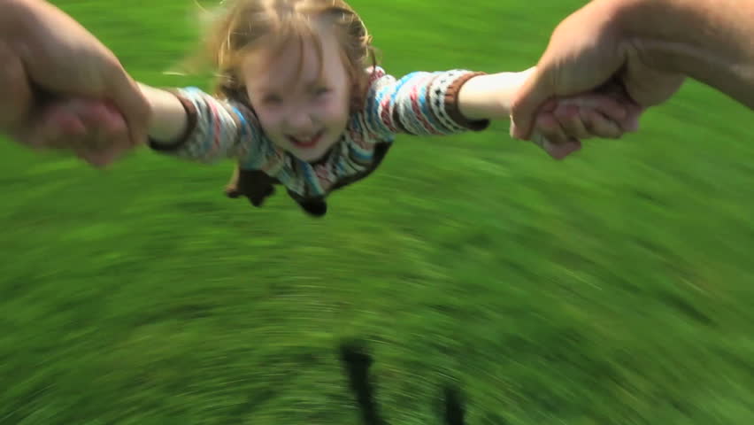 Point-of-view shot of a father spinning his young daughter around in their yard 