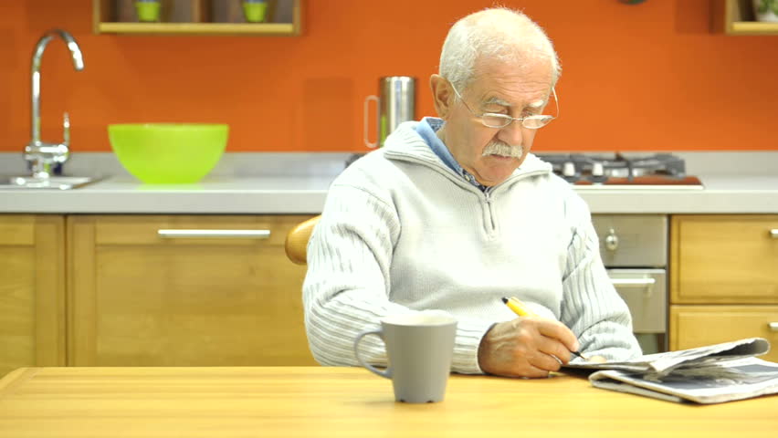 Senior man doing crossword puzzle, then smiling at camera;  HD: Photo JPEG.