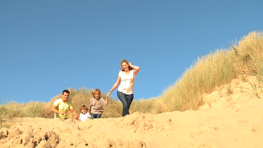 Attractive young caucasian family enjoying leisure time together on coastal sand dunes  filmed at 60FPS