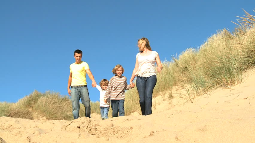 Attractive young caucasian family enjoying leisure time together on coastal sand dunes  filmed at 60FPS