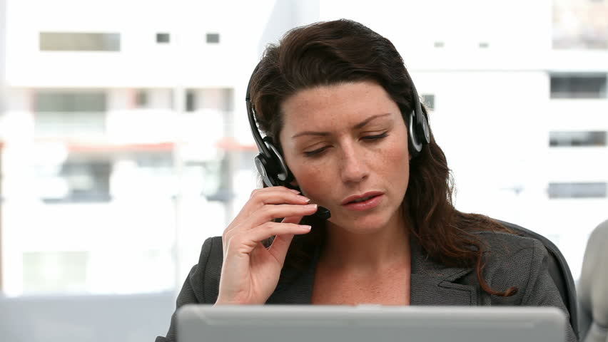 Unhappy woman talking on the headphone in an office