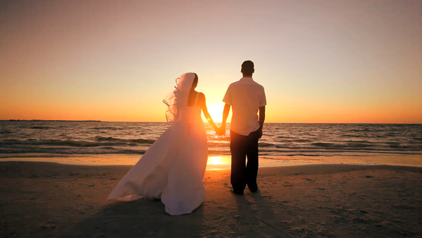 Attractive couple exchanging a kiss after their sunset wedding 