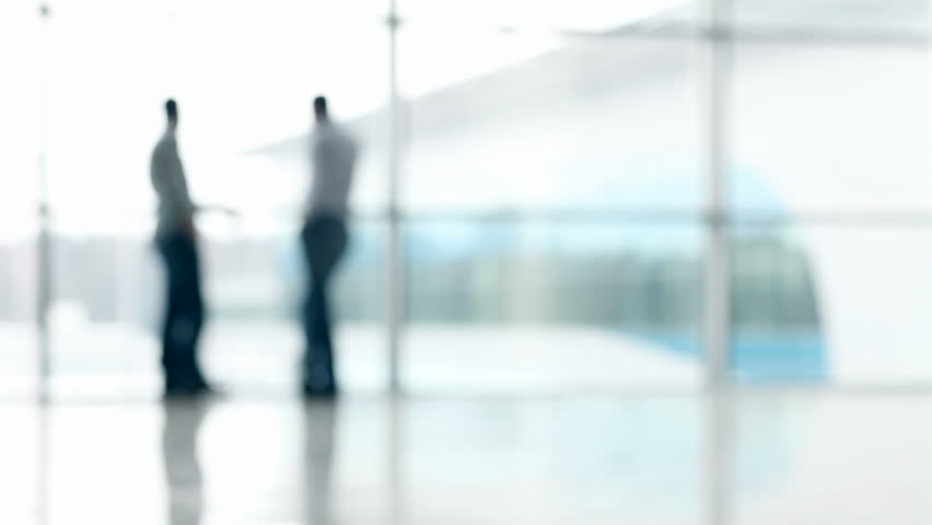 Two men defocused in hall of office building