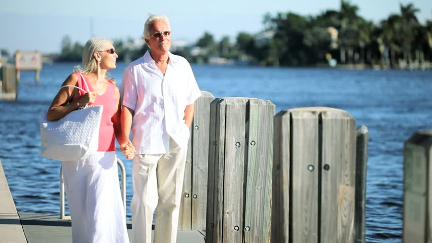 Healthy senior couple enjoying leisure in their retirement walking by a waterway