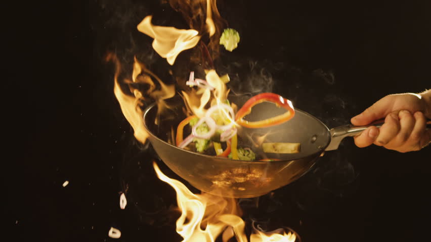 Chef Frying vegetables on fire throwing them in a frying pan