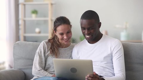 480px x 270px - Happy mixed ethnicity young couple using laptop for ecommerce doing online  shopping together watching video movie sitting on sofa, smiling african man  and caucasian woman looking at computer at home
