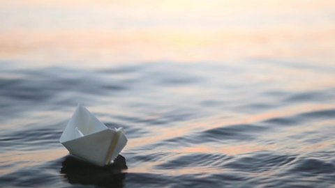 A Paper Boat Is Floating On The Waves In The Water At A Beautiful Sunset Origami Ship Sailing The Concept Of A Dream Future Childhood Freedom Or Hope Slow Motion