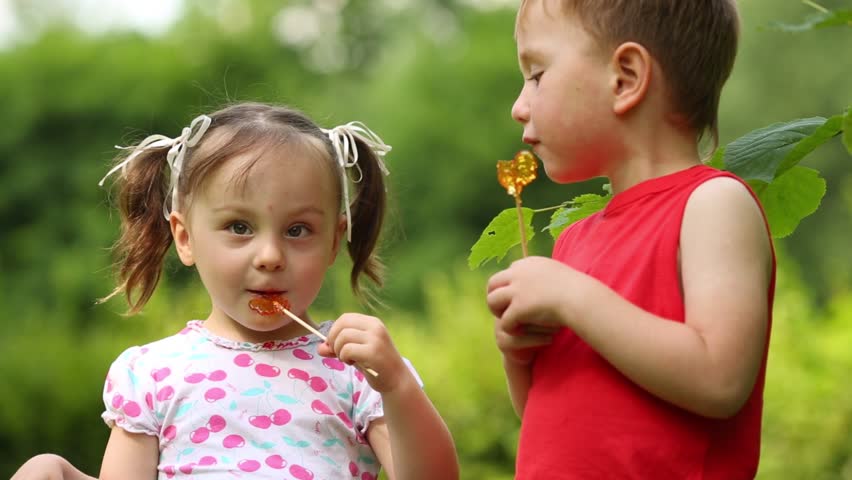 Two Cute Children Are Sitting On Bench In Park And Looking At Each ...