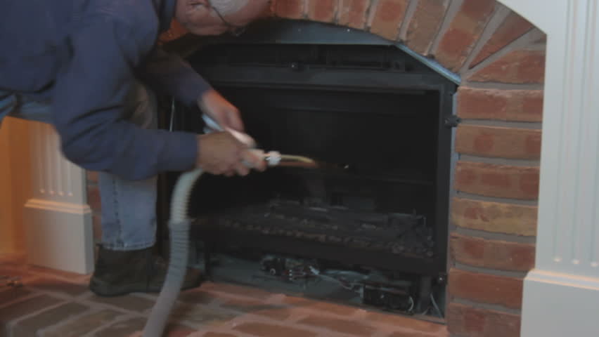 Man Cleaning And Maintaining Home Gas Fireplace