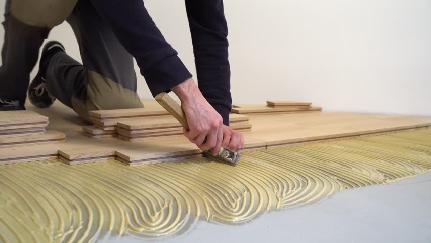 Carpenter Worker Installing Wood Parquet Board During Flooring Carpenter Worker Installing Wood Parquet Construction In A Renovated Room Installation Of