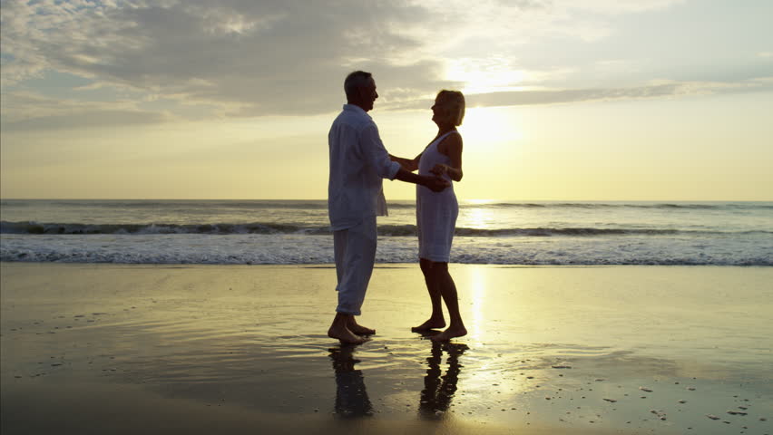 Two Model Released Women Walking Together, Holding Hands On Beach At ...