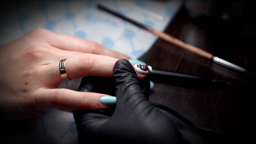 Nail Technician In Black Gloves Deals On Fingers Customer Care Manicurist In Black Gloves Gets A Top Coating On The Nail With Drawing Of Penguin