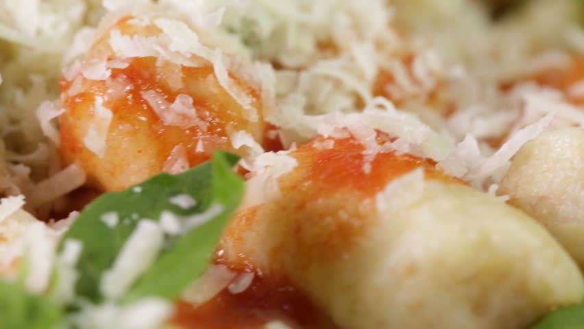 Italian food potato gnocchi in a white dish for a restaurant with grated cheese falling down.