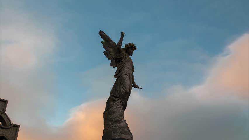 Angel Statue In The Sunset Light Against Fast Moving Clouds And Evening ...