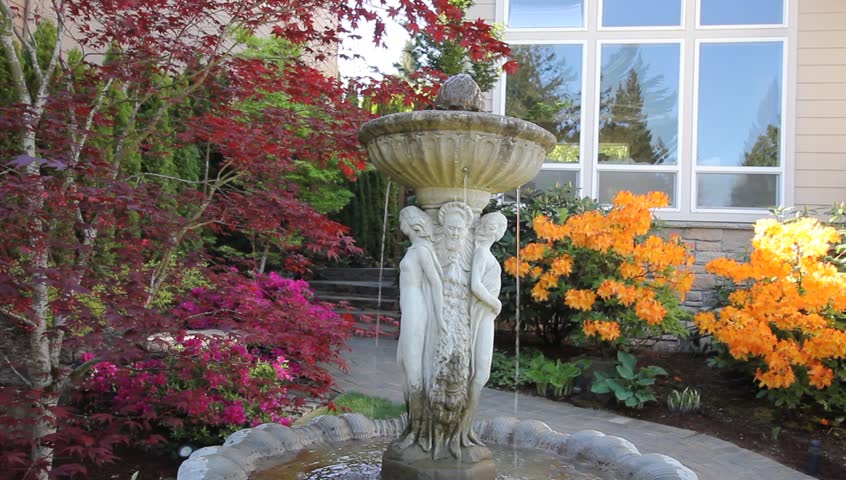 Stock video of frontyard garden with water fountain, flowering