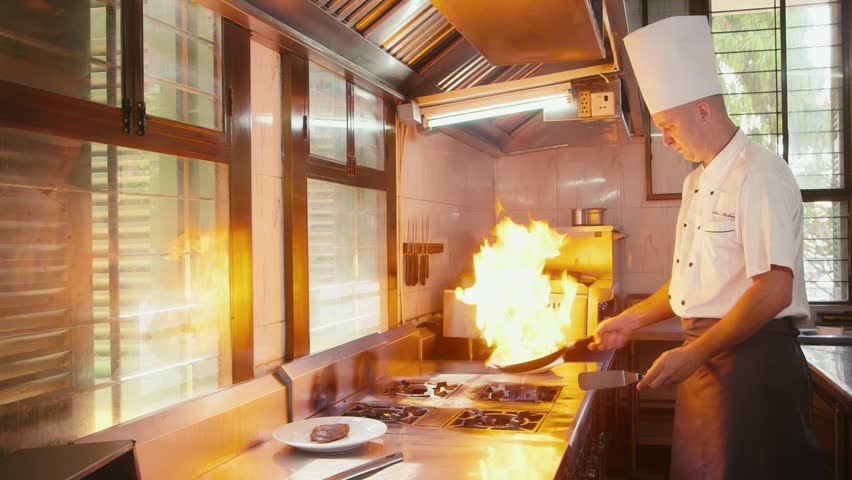 Restaurant Kitchen Chefs professional chef in a commercial kitchen cooking flambe style Restaurant Kitchen Chefs professional chef in a commercial kitchen cooking flambe style