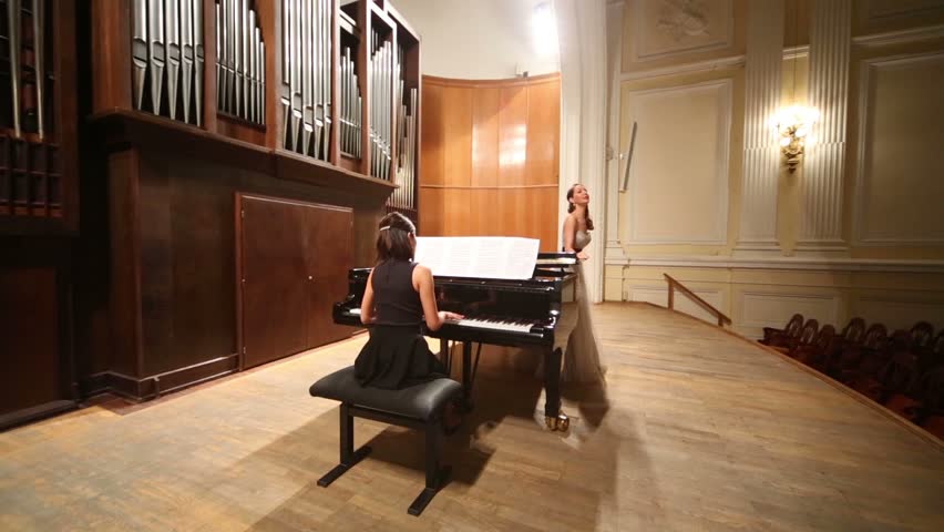 Back View Woman Pianist Sits At The Piano In Concert Stage Stock