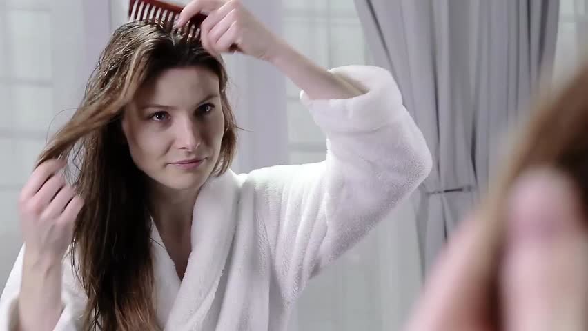 Hd00 26a Young Woman In A Robe Looks Into A Mirror As She Brushes
