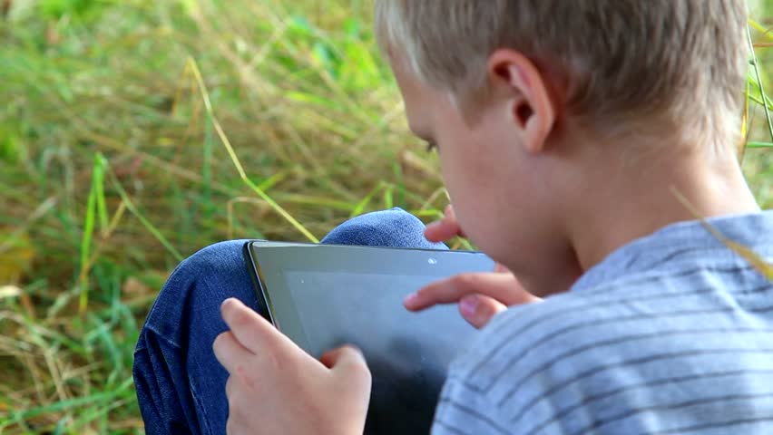 The boy is playing the computer. Девочка исследует мальчика. the boy is playing computer games. мальчик изучает по телевизору документальный фильм о природе. boy playing on tablet.